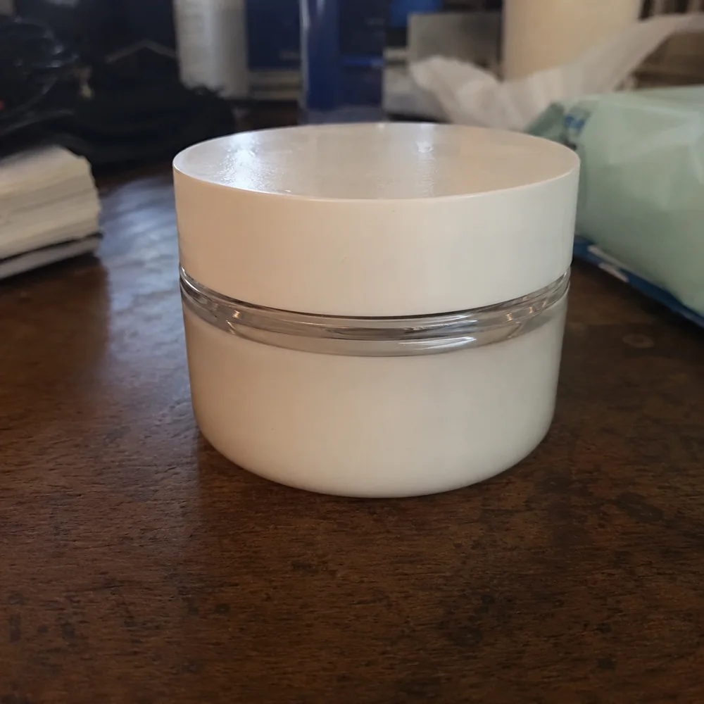 Before — an amateur phone photo of a cosmetic cream jar on a cluttered table