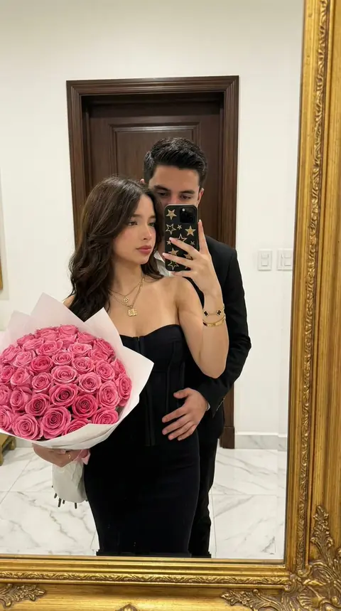 Couple's mirror selfie in a hotel suite full of warm gold light