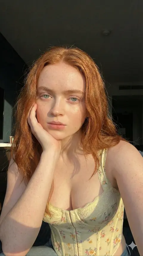 Sunlit close-up of a freckled blonde girl smiling softly
