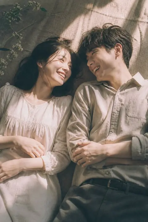 Couple lying side by side smiling in soft window light