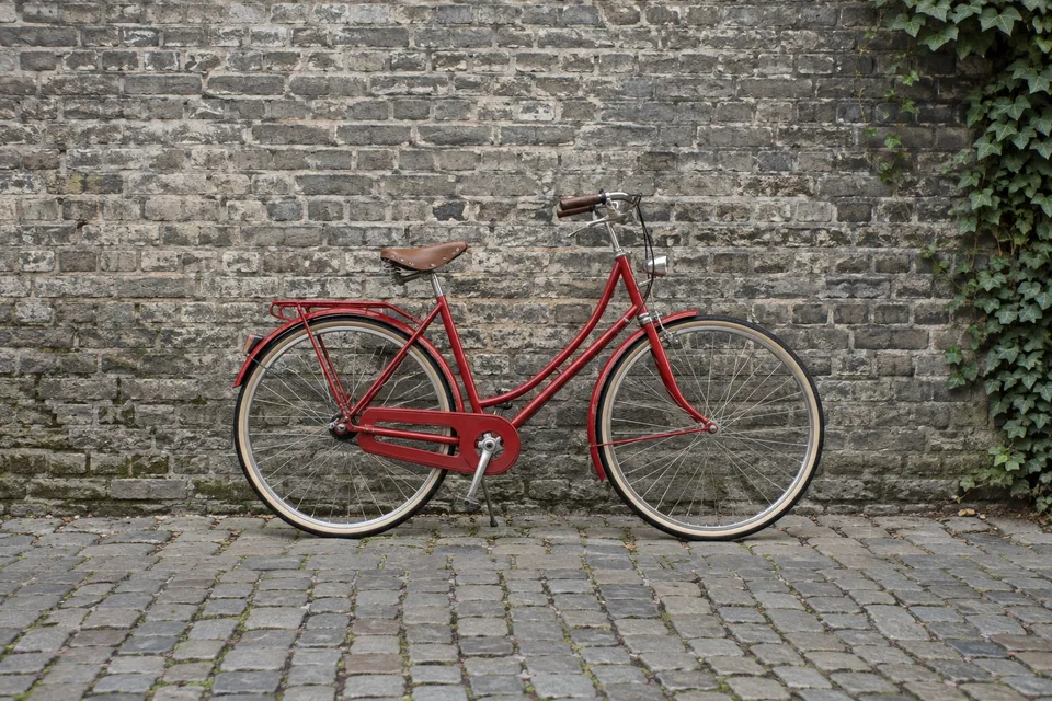 A red bicycle against a gray brick wall under neutral daylight
